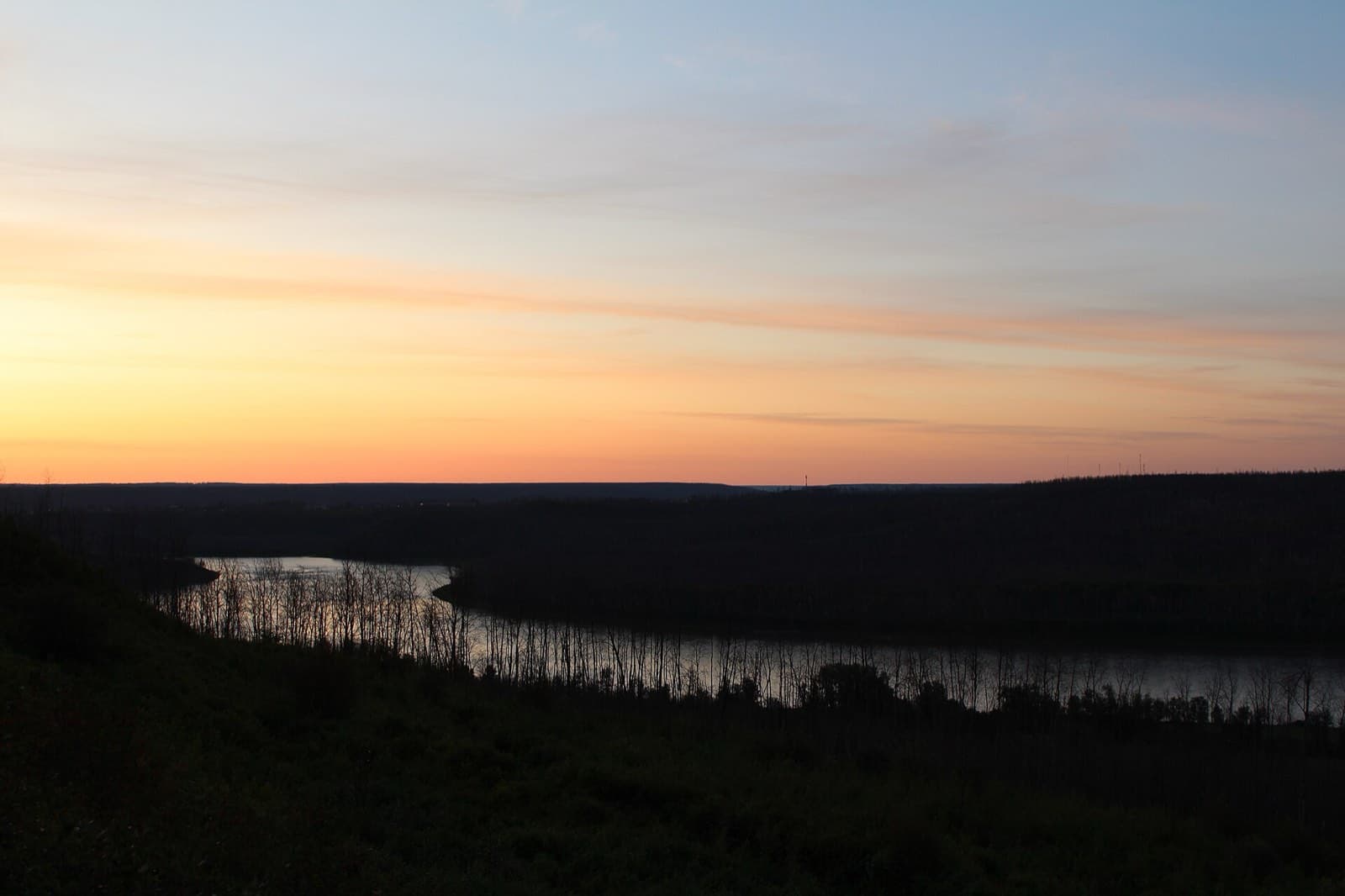 Orange sunrise sky over the boreal forest and the Athabasca River valley at Fort McMurray, Alberta
