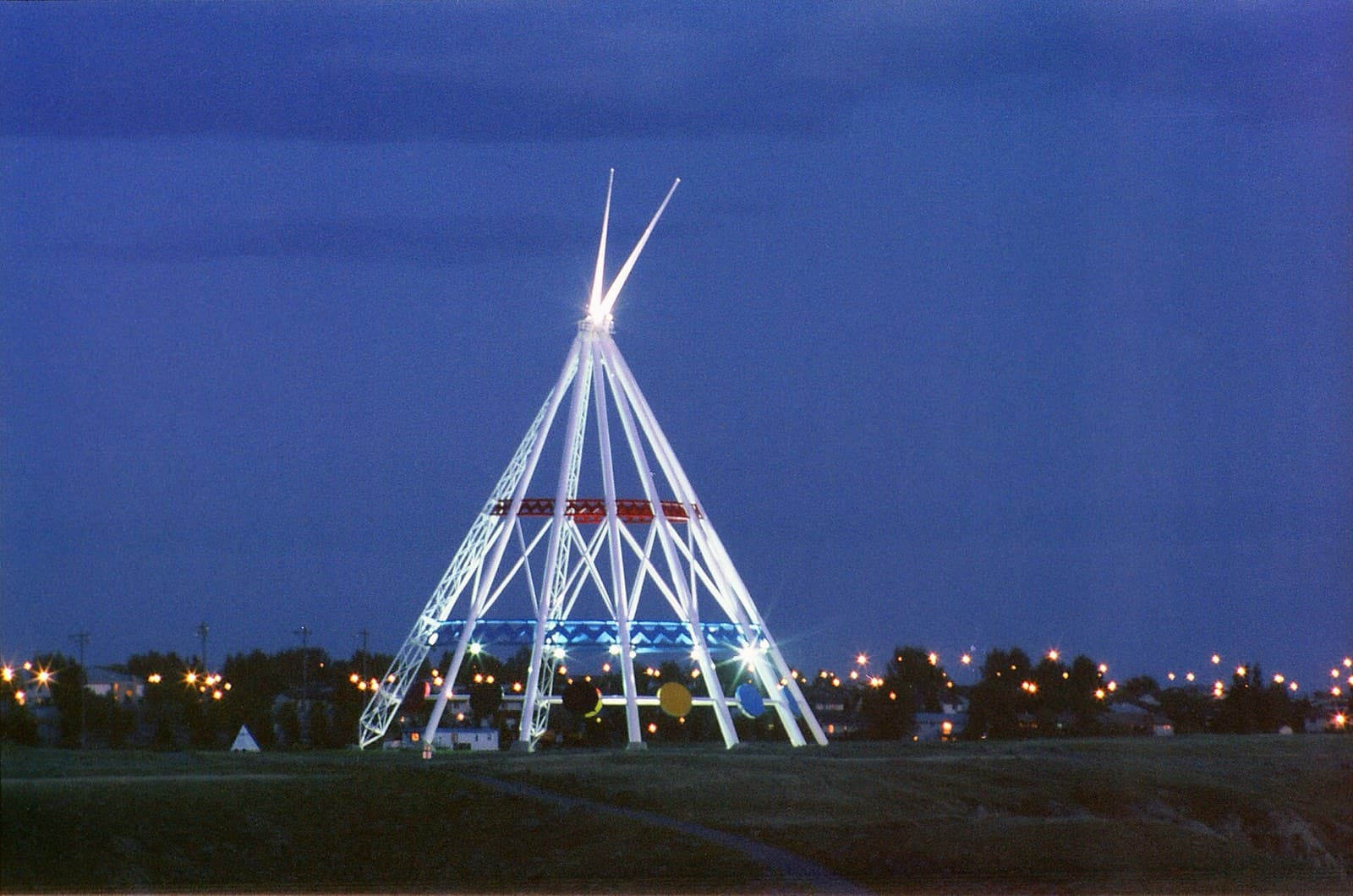 The white steel Saamis Tepee glowing against a deep blue night sky at the entrance to Medicine Hat, Alberta